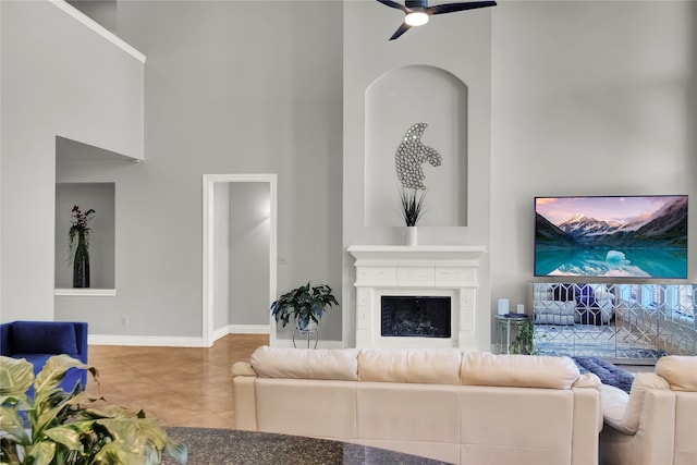 living room with tile patterned floors, ceiling fan, and a towering ceiling