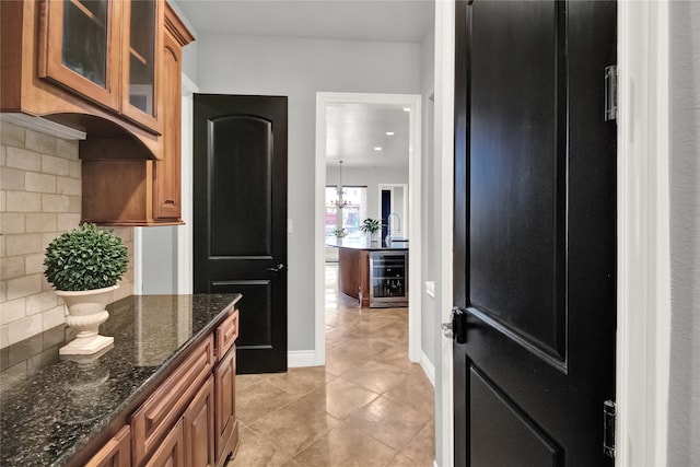 kitchen with dark stone countertops, light tile patterned floors, refrigerator, wine cooler, and decorative backsplash