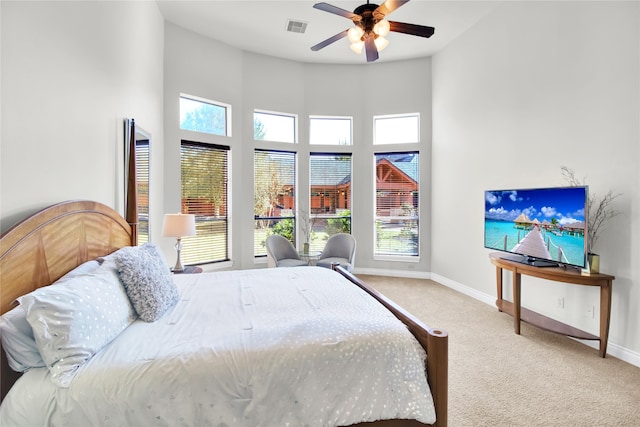 carpeted bedroom featuring ceiling fan and a high ceiling