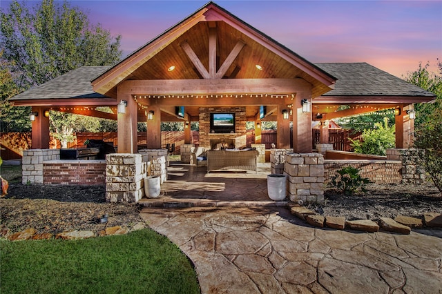 patio terrace at dusk with an outdoor living space with a fireplace and a gazebo