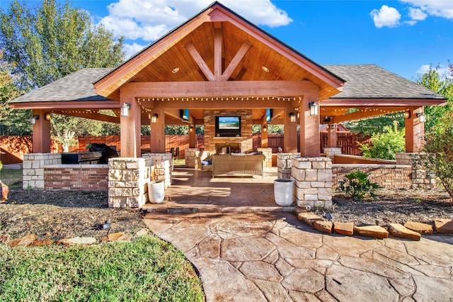 view of patio with an outdoor living space with a fireplace and a gazebo