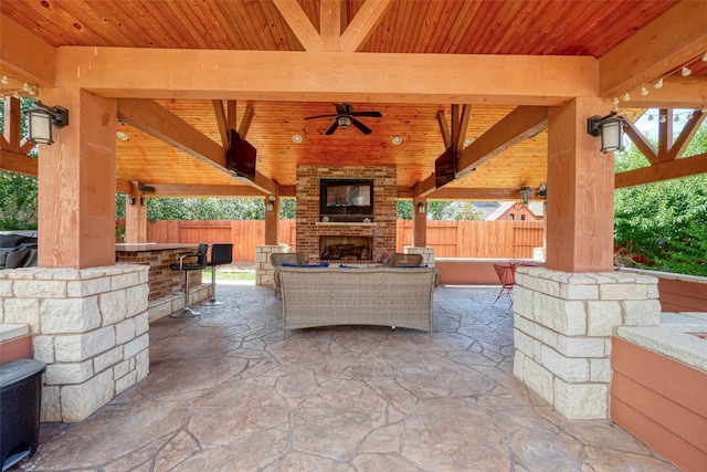 view of patio / terrace featuring an outdoor brick fireplace, ceiling fan, and a gazebo