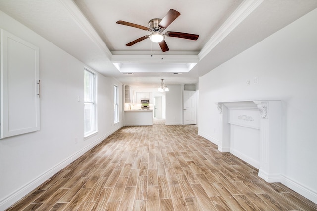 unfurnished living room with a tray ceiling, ceiling fan, crown molding, and light hardwood / wood-style floors