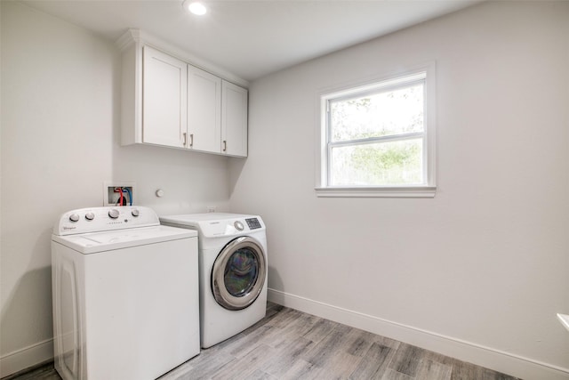 laundry room with independent washer and dryer, cabinets, and light hardwood / wood-style floors