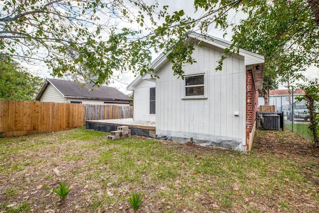 rear view of house featuring central AC unit and a lawn