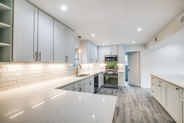 kitchen with decorative light fixtures, sink, stainless steel appliances, and white cabinetry