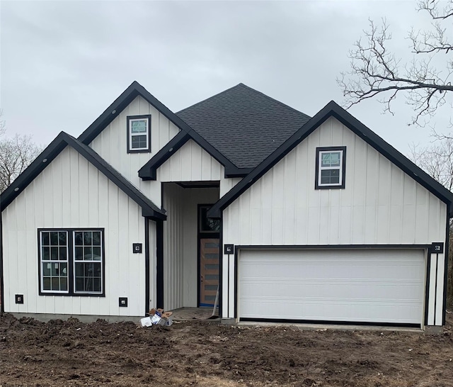 modern inspired farmhouse featuring dirt driveway, a shingled roof, board and batten siding, and an attached garage