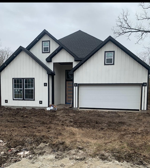 modern inspired farmhouse featuring driveway, a garage, board and batten siding, and roof with shingles