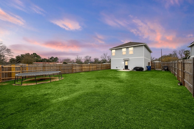 yard at dusk with a trampoline and a patio area