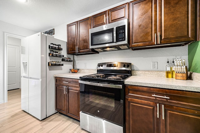 kitchen featuring appliances with stainless steel finishes, dark brown cabinets, and light hardwood / wood-style floors