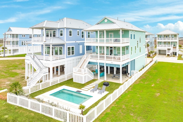 rear view of house with a fenced in pool, a lawn, a patio area, and a balcony