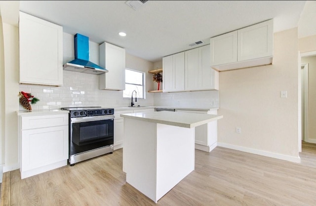 kitchen featuring white cabinets, a center island, electric stove, and wall chimney exhaust hood