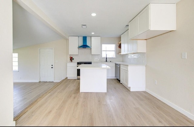 kitchen featuring white cabinetry, stove, a kitchen island, tasteful backsplash, and wall chimney exhaust hood