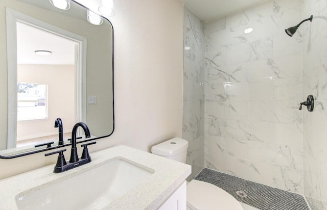 bathroom featuring vanity, tiled shower, and toilet