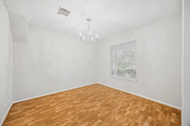 spare room with light hardwood / wood-style flooring and a notable chandelier