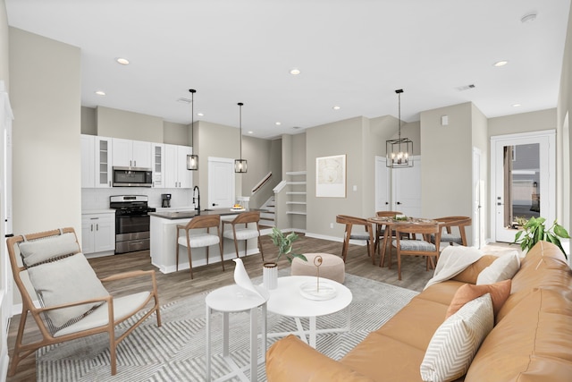 living area with stairs, recessed lighting, a chandelier, and wood finished floors