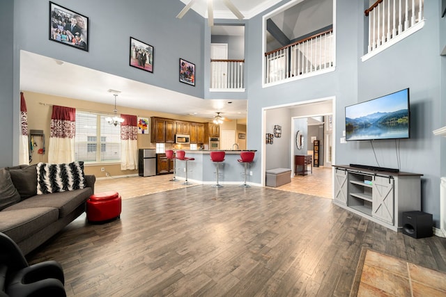 living room with light wood-type flooring and ceiling fan with notable chandelier