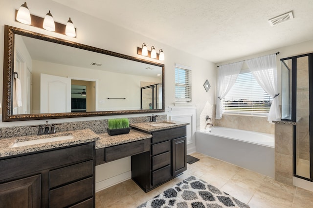 bathroom featuring plus walk in shower, vanity, a textured ceiling, and tile patterned floors