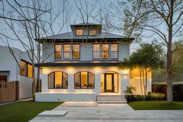 back of house with fence, a lawn, and stucco siding