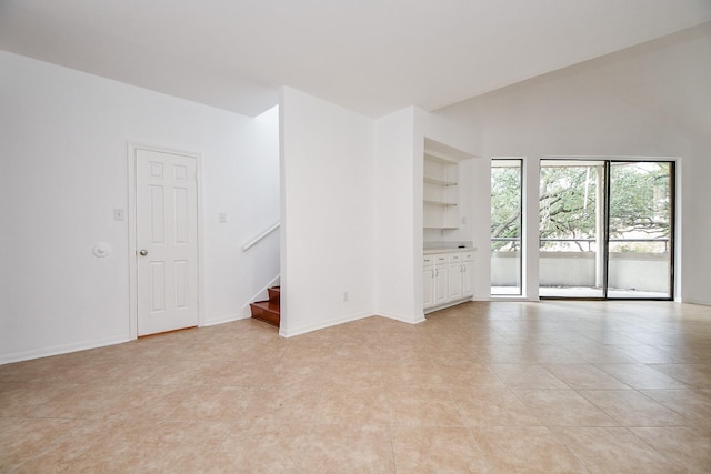 tiled empty room featuring vaulted ceiling and built in shelves