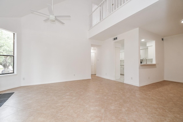 tiled empty room featuring a towering ceiling and ceiling fan