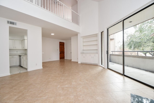 unfurnished living room with a towering ceiling and light tile patterned floors