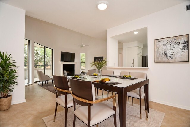 dining space with visible vents, lofted ceiling, a fireplace, baseboards, and ceiling fan