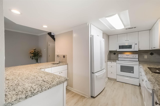 kitchen with white cabinets, white appliances, light wood finished floors, and a sink