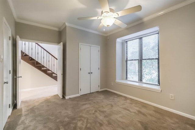 unfurnished bedroom with carpet floors, a closet, crown molding, and baseboards