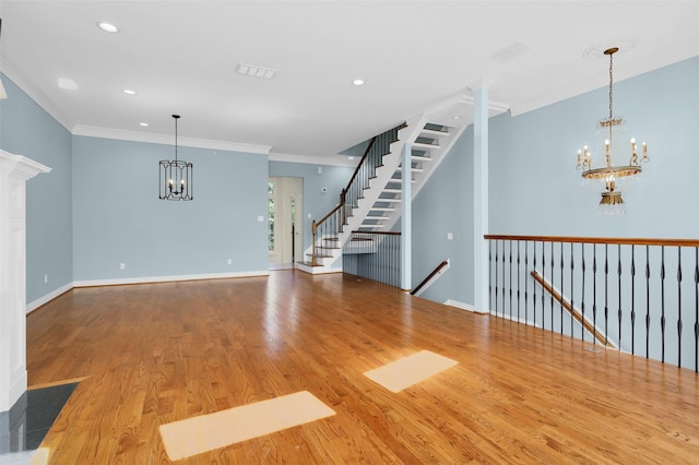 unfurnished living room with a notable chandelier, wood finished floors, baseboards, ornamental molding, and visible vents