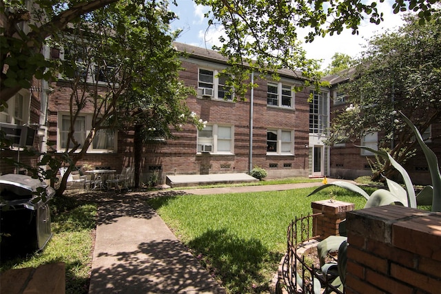 exterior space with a yard, cooling unit, and brick siding