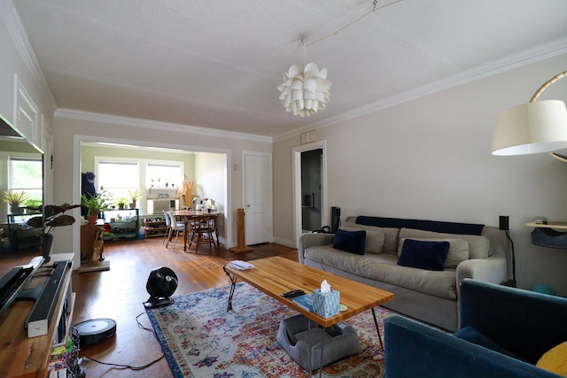 living area featuring a notable chandelier, ornamental molding, and wood finished floors