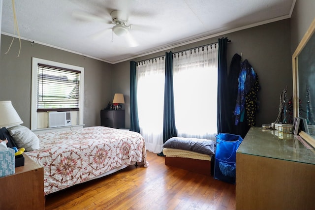 bedroom with ornamental molding, cooling unit, wood finished floors, and a ceiling fan