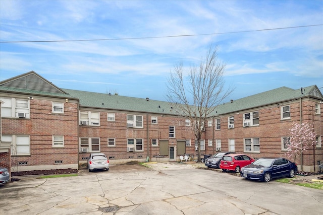 view of property with uncovered parking and cooling unit