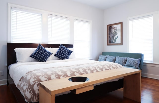 bedroom with multiple windows, dark wood finished floors, and baseboards