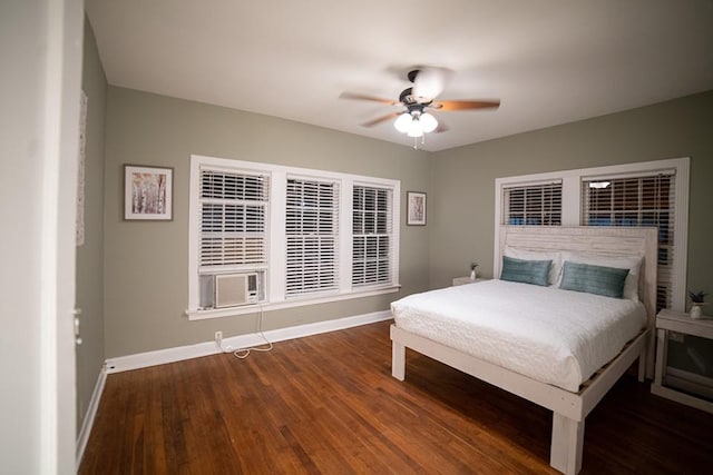 bedroom featuring dark wood-style floors, baseboards, and cooling unit