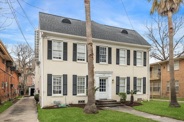 view of front of home featuring brick siding, crawl space, a shingled roof, and a front lawn