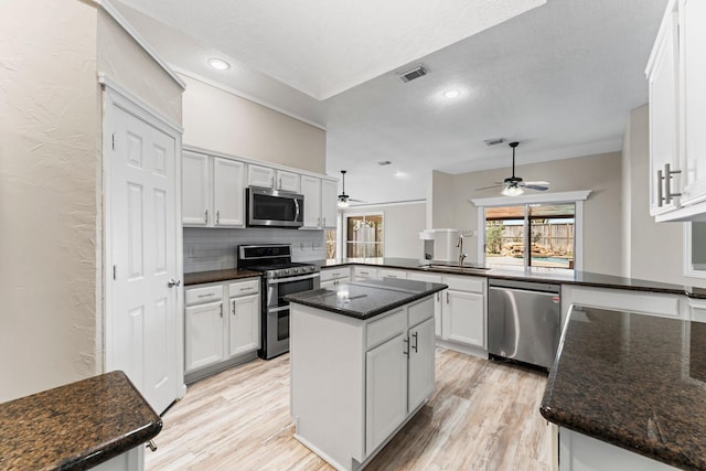 kitchen with sink, a center island, stainless steel appliances, kitchen peninsula, and white cabinets