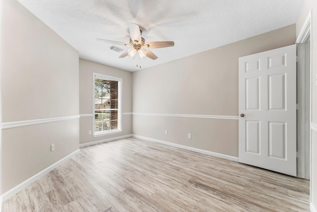 empty room with ceiling fan, light hardwood / wood-style flooring, and a textured ceiling