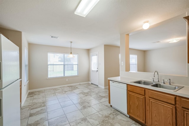 kitchen with white appliances, sink, light tile patterned flooring, and decorative light fixtures