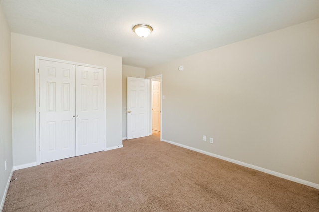 unfurnished bedroom with light carpet and a closet