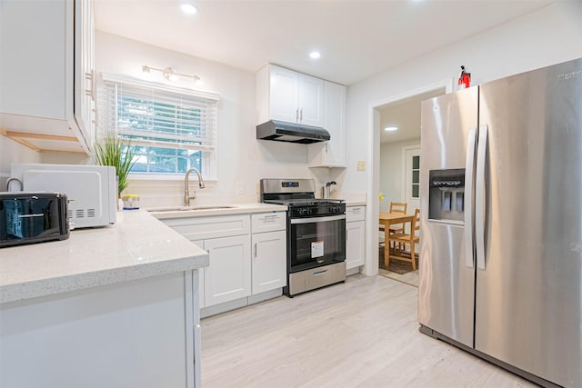 kitchen with sink, white cabinets, stainless steel appliances, and light wood-type flooring