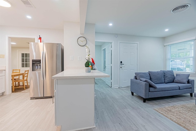 kitchen featuring white cabinets, stainless steel fridge, and light hardwood / wood-style floors