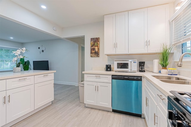 kitchen with dishwashing machine, light hardwood / wood-style flooring, sink, range with gas stovetop, and white cabinets