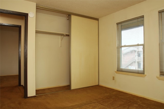 418 Garland Dr Unit 222, Lake Jackson, TX 77566 - unfurnished bedroom with a textured ceiling, a closet, dark carpet, and baseboards