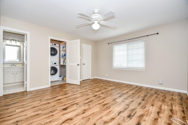 unfurnished bedroom featuring ensuite bathroom, light hardwood / wood-style flooring, stacked washer and clothes dryer, and sink