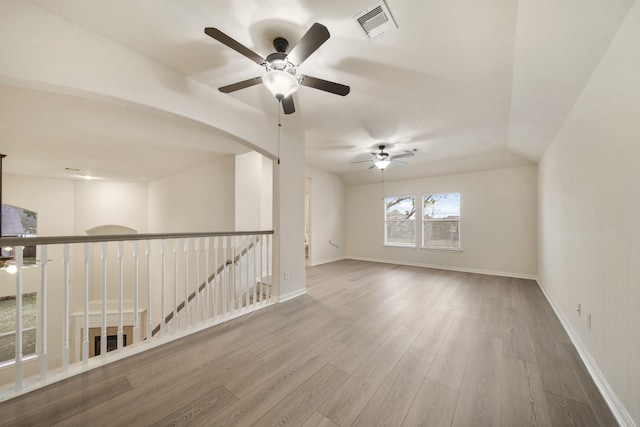 spare room featuring baseboards, visible vents, ceiling fan, and wood finished floors