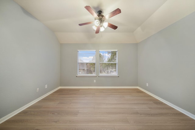 unfurnished room with light wood-style floors, vaulted ceiling, baseboards, and ceiling fan