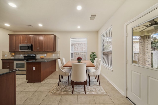 kitchen featuring light tile patterned flooring, stainless steel appliances, visible vents, tasteful backsplash, and dark countertops