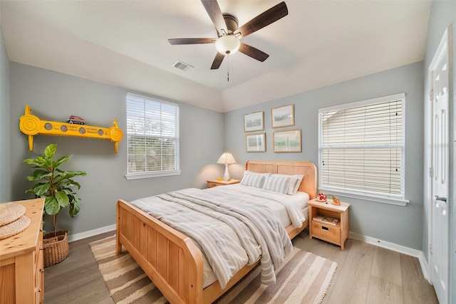 bedroom with baseboards, visible vents, ceiling fan, and light wood finished floors